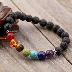 Handmade seven chakra volcano stone beaded bracelet on a vintage wood background
