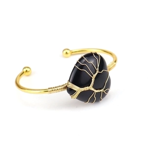 Detailed view of handmade gold wire-wrapped obsidian heart pendant on an open bangle