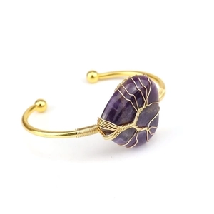 Macro detail of handmade Tree of Life wire wrap on purple amethyst gemstone gold bangle