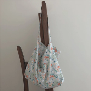Detailed view of floral canvas tote bag with daisy patterns hanging on a wooden rack