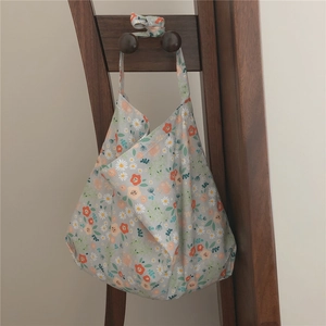 Detailed close-up of a floral cotton shoulder bag with orange and white daisy patterns