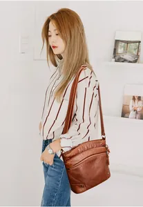 Detail of vintage brown leather crossbody bag featuring multi-zipper pockets and soft texture