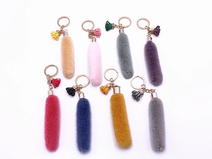 Detailed view of colorful plush tail keychains in pink, yellow, blue, and grey variety