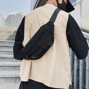 Detailansicht einer schwarzen taktischen Canvas-Brusttasche an einem Model im urbanen Bereich