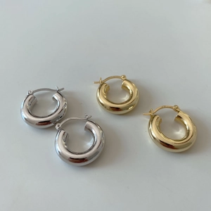 Macro detail of thick C-shaped hoop earrings in polished silver and gold finishes