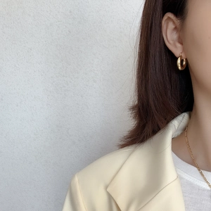 Close-up of model wearing gold C-shape hoop earrings in minimalist polished metal finish