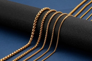 Detail view of various thicknesses of golden box chain necklaces on a jewelry display