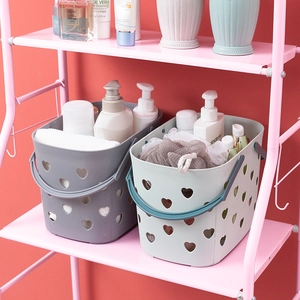 Gray and green plastic shower baskets with heart-shaped cutouts on a pink metal rack