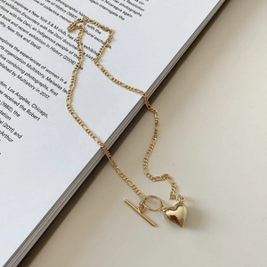 Close-up of gold 925 silver heart necklace with Figaro chain and toggle clasp on book