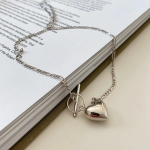 Detail of silver heart pendant with OT toggle clasp and Figaro chain on a magazine