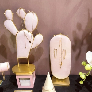 Golden letter pendant earrings and necklaces on pink velvet cactus display stand