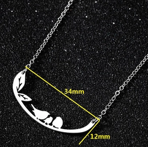 Detail view of bird and leaf pendant showing dimensions 34mm by 12mm on black background