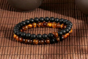 Close-up of matte black agate and tiger eye stone bead bracelets on bamboo mat