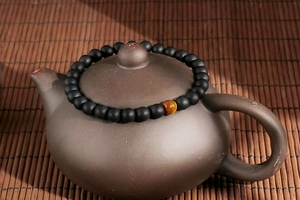 Tiger eye and matte black agate beaded bracelet displayed on a traditional ceramic lid