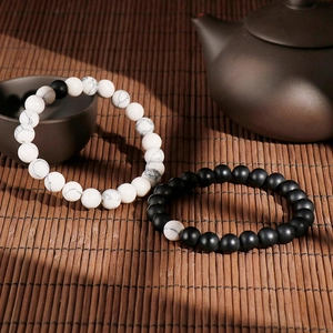 Elastic beaded bracelets with white turquoise and matte black agate on bamboo background