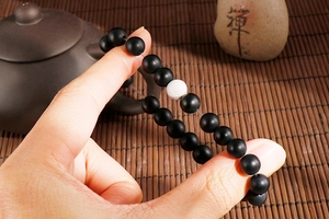 Macro detail of matte black beads and white turquoise bead on elastic bracelet