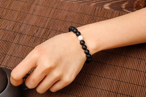Detail of white turquoise and matte black bead stretch bracelet on a model wrist