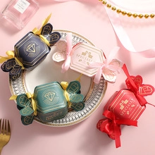 Detailed view of candy-shaped gift boxes with gold foil text and silk ribbons