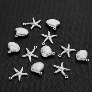 Macro shot of silver hollow starfish and seashell pendants on a dark textured background