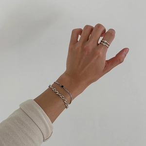 Detail of 925 sterling silver twisted chain bracelets and rings on a model's hand