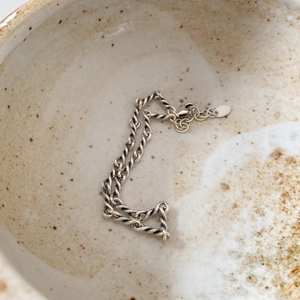 Close-up of twisted 925 sterling silver rope chain bracelet with lobster clasp in a bowl