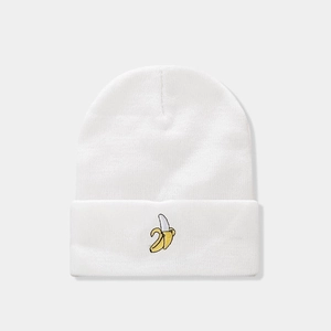Close-up of white knitted beanie featuring detailed yellow banana embroidery on the cuff