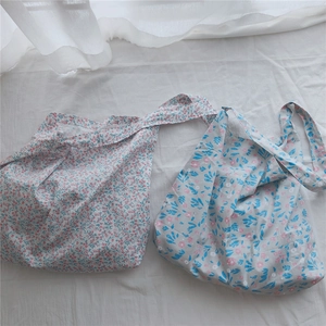 Close-up of two floral cotton tote bags with pink and blue prints on white linen