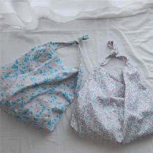 Flat lay detail of floral cotton shoulder bags with elegant knotted strap designs