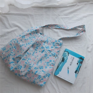 Detail of light blue floral cotton tote bag with pink blossoms and wide shoulder strap