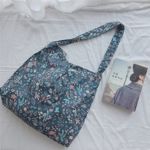 Floral canvas tote bag with colorful botanical prints shown on a white wrinkled sheet