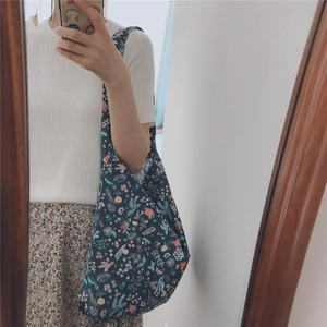 Detail of dark blue cotton tote bag featuring colorful floral patterns and shoulder strap