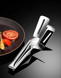 Close-up of stainless steel spatula tongs with slotted design for oil drainage and flipping