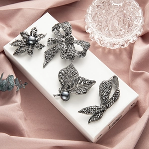 Vintage brooch set with black pearls and rhinestones on elegant silk background