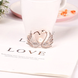Broche double cygne en or rose avec cristaux scintillants et perle blanche centrale
