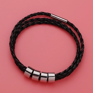 Black braided leather bracelet with four silver stainless steel beads on pink background