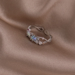 Close-up of shell flower ring with iridescent stones on champagne silk fabric