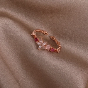 Macro shot of rose gold open ring with floral gemstone details on champagne silk