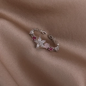 Close-up of silver flower ring with pink stones on elegant champagne silk fabric