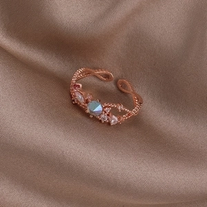 Detail of rose gold open ring with crystals and zircon on beige silk fabric
