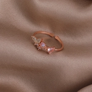Detail of rose gold shell flower ring with pink heart stone on brown silk background