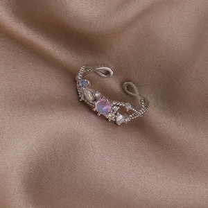 Macro shot of silver pearl shell flower ring with purple gemstone and zircon on brown silk