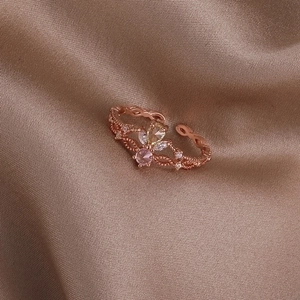 Detail of rose gold ring with pear-cut yellow gem and pink stone on champagne satin