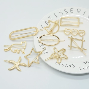 Detailed close-up of golden metal hair clips in star, heart and cat shapes on a white plate