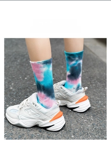 Detailed close-up of pink and blue tie-dye cotton socks with white sneakers on asphalt