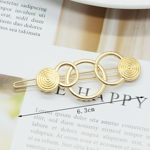 Detail of 6.3cm gold hollow geometric hair clip on minimalist white card background