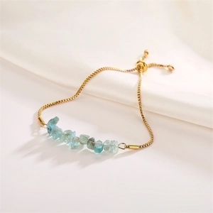 Detail of light blue crystal stone beads on a gold adjustable box chain bracelet