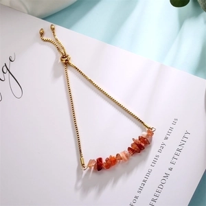 Detail of adjustable golden chain bracelet with irregular orange natural stone chips