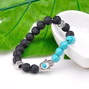 Lava stone and turquoise Hamsa Hand beaded bracelet on a green leaf and ceramic plate