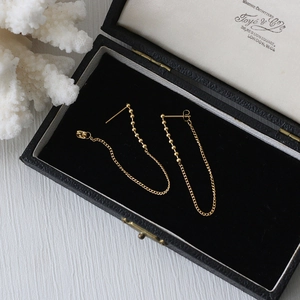 Detail of long gold chain tassel earrings with metal beads in a vintage jewelry box