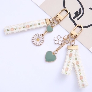 Daisy flower embroidery keychain with gold hardware and heart charms on white background